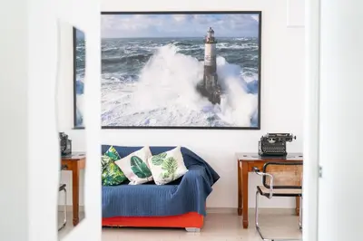 a living room with a blue couch and a lighthouse in the ocean at Villa Uluvud with Pool Gym Sauna in Alcamo