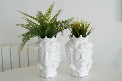 two white vases with plants in them on a table at Villa Uluvud with Pool Gym Sauna in Alcamo