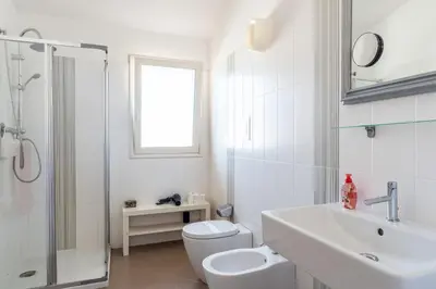 a white bathroom with a toilet and a sink at Villa Uluvud with Pool Gym Sauna in Alcamo