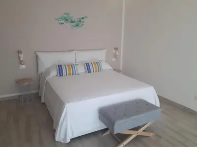 a bedroom with a large white bed and a stool at Casa di Magda in Castellammare del Golfo