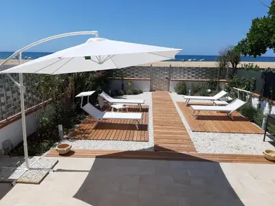 a patio with an umbrella and chairs and the beach at DORIDE Appartamento sulla spiaggia in Balestrate