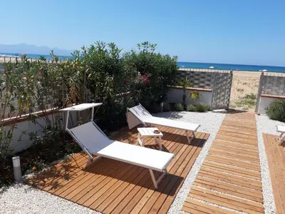 a wooden deck with two white chairs and the beach at DORIDE Appartamento sulla spiaggia in Balestrate