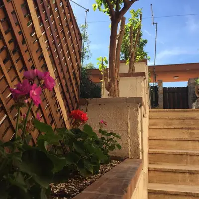 a fence with stairs and flowers next to a tree at George House Mondello 32 in Mondello