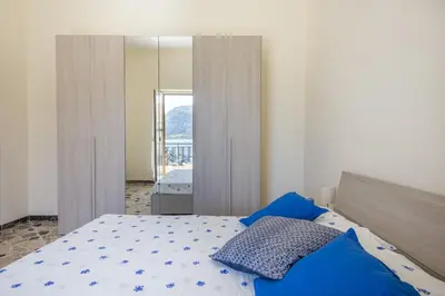 a bedroom with a bed with blue sheets and a mirror at Casetta Vista Mare in Piazza a Mondello by Wonderful Italy in Palermo