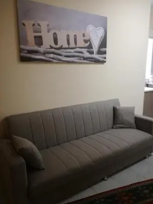 a couch in a living room with a sign on the wall at Giusy's Place 1 in Campofelice di Roccella