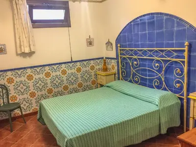 a bedroom with a bed with a blue headboard at VILLA VENERE con vista sul mare in San Vito lo Capo