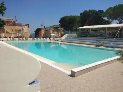 a large swimming pool with chairs and a building at Casa Vacanze Mondello Mare Piscina ALBAMAOR in Mondello