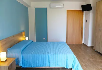 a bedroom with a blue bed and a television at Bed Ponente in Isola delle Femmine