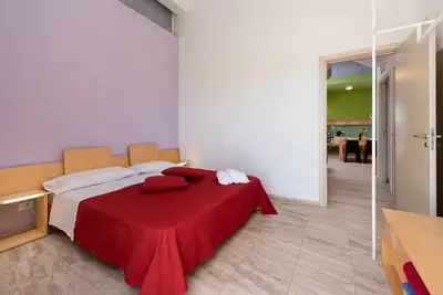 a bedroom with a bed with a red blanket on it at Vitorno Residence in San Vito lo Capo