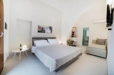a white bedroom with a bed and a couch at Baglio La Riserva in Scopello