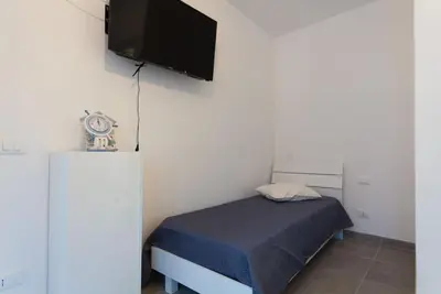 a small bedroom with a bed and a flat screen tv at Casa Leonardo e Romeo in Castellammare del Golfo