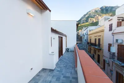 a narrow alley with white buildings and a mountain at Casa Leonardo e Romeo in Castellammare del Golfo