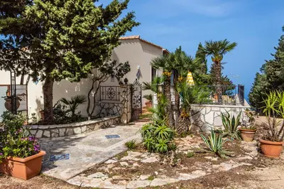 a house with a fence and trees and plants at Villa Verde con vista sul mare in San Vito lo Capo