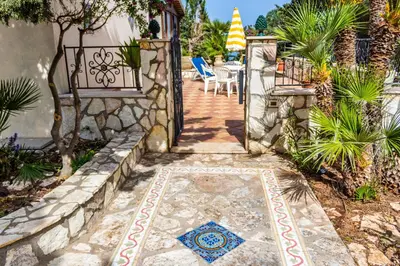 a walkway leading to a patio with a table and chairs at Villa Verde con vista sul mare in San Vito lo Capo
