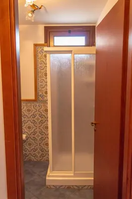 a sliding glass door with a window in a bathroom at Villa Azzurra con vista sul mare in San Vito lo Capo