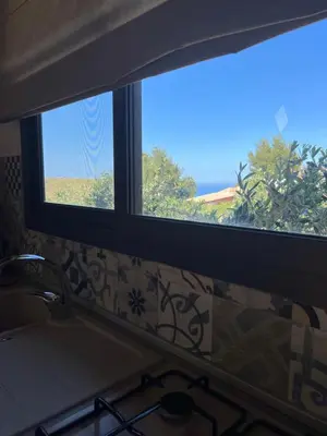 a kitchen window with a view of the ocean at Baglio cracchiolo da tuzzo Villa Ulivo in San Vito lo Capo