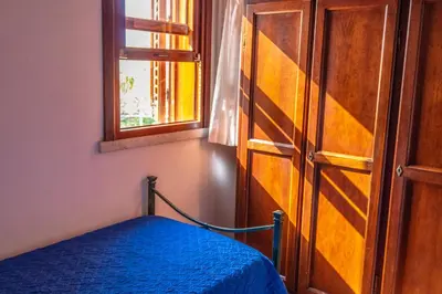 a bedroom with a blue bed and a window at Baglio Cracchiolo da Tuzzo - Casa Carrubbo in San Vito lo Capo