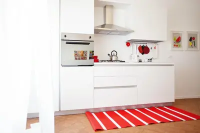 a kitchen with white cabinets and a red and white rug at GIULIA E CHIARA LUXURY APARTMENT in Castellammare del Golfo