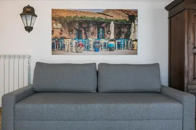 a couch in a living room with a painting on the wall at Corte del Merlo in Palermo