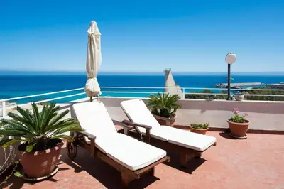 a patio with two lounge chairs and the ocean at Casa con Terrazza sul Mare all'Addaura by Wonderful Italy in Palermo