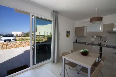 a kitchen with a table and a dining room with a view at Villa Vitruvio - Giardino degli Allori Scopello in Castellammare del Golfo