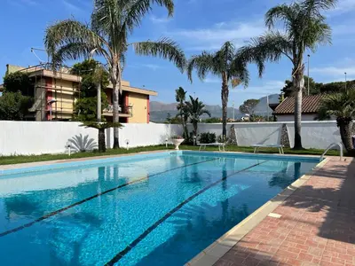 a swimming pool with palm trees and a building at Casa vacanze Villa Grace in Villagrazia