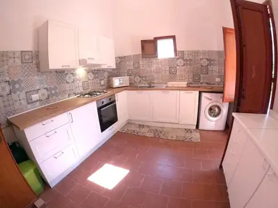 a kitchen with white cabinets and a washer and dryer at Villa Marilù in Castellammare del Golfo