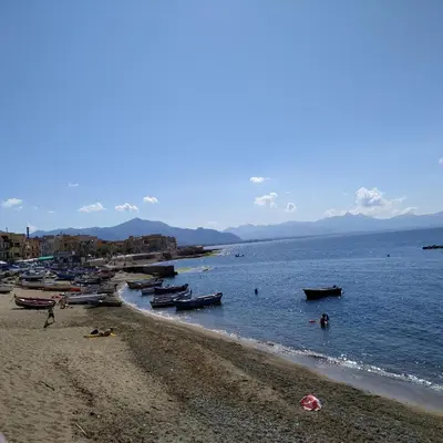 a beach with boats and people in the water at Aspra al delfino blu in Bagheria