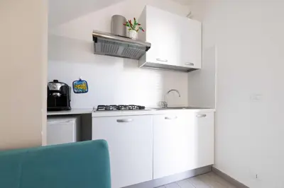 a small kitchen with white cabinets and a blue chair at Appartamenti centro storico Milazzo Annarita in Castellammare del Golfo