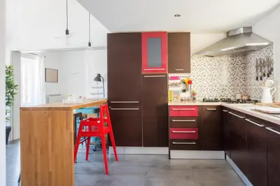 a kitchen with brown cabinets and a red stool at Terrazza dei Colori alla Kalsa by Wonderful Italy in Palermo