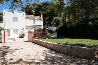 a white house with a red gate and a yard at Villa Gina con vista mozzafiato sul golfo di Macari in Macari