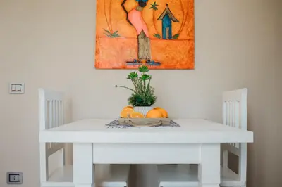 a white table and chairs with a painting on the wall at Giardini del Golfo Villa al Mare in Balestrate