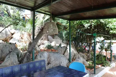 a table and chairs under a pavilion with a rock garden at Casa Elvira in Terrasini