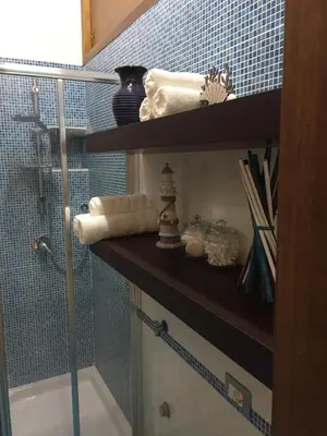a bathroom with a shower and a shelf with towels at Terra e Mare in Capaci