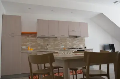 a kitchen with white cabinets and a table with chairs at Acqua Chiara Appartamenti in San Vito lo Capo
