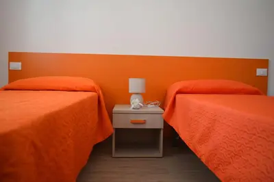 two beds in a room with orange walls at Acqua Chiara Appartamenti in San Vito lo Capo