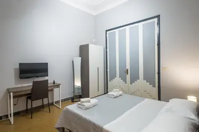 a bedroom with a bed and a desk and a television at GiaChi friendly rooms alla Stazione in Palermo