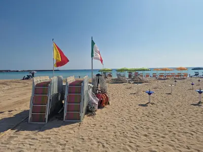 a beach with some flags and chairs on the sand at Casa Sabrina in San Vito lo Capo