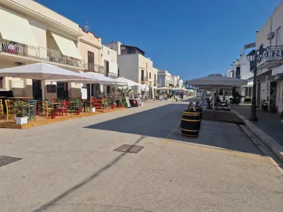 an empty street with tables and umbrellas in a town at Casa Sabrina in San Vito lo Capo