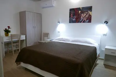 a bedroom with a bed and a desk and a painting on the wall at Opera Boutique Rooms in Monreale