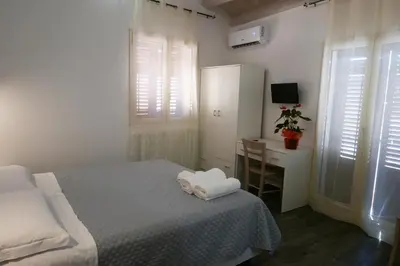 a bedroom with a bed and a desk with a television at Opera Boutique Rooms in Monreale