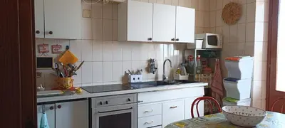 a kitchen with white cabinets and a sink and a table at Casa Vacanza nell'Orto in Termini Imerese