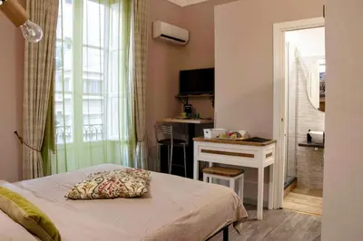 a bedroom with a bed and a desk and a window at B&B Benincasa in Palermo