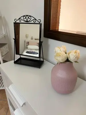 a vase with flowers sitting on a table with a mirror at Lisetta's house in Monreale
