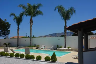 a swimming pool with palm trees in a resort at villa Roby in Trappeto