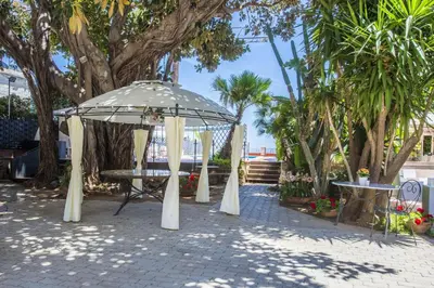a gazebo in a park with trees and palm trees at B&B Villa Liberty sul Mare by Wonderful Italy in Palermo