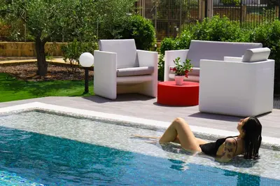a woman laying in the water next to a swimming pool at b&b Pirriera in Bagheria