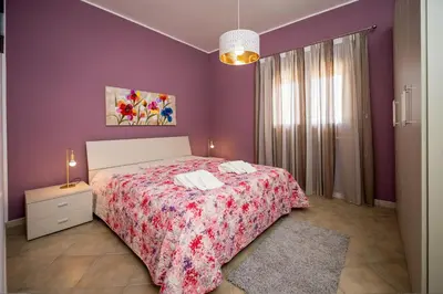a bedroom with a bed and a purple wall at Villa Mirto in Castellammare del Golfo