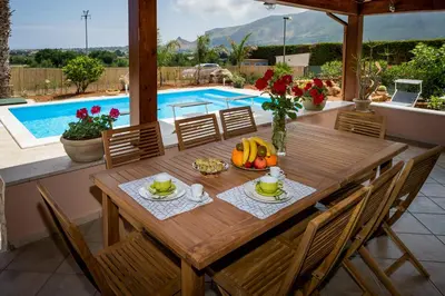 a wooden table with a bowl of fruit next to a pool at Villa Mirto in Castellammare del Golfo