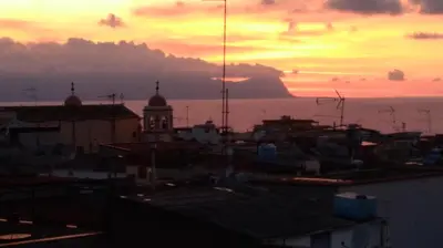 a sunset over a city with a clock tower at La Balestra B&B in Balestrate